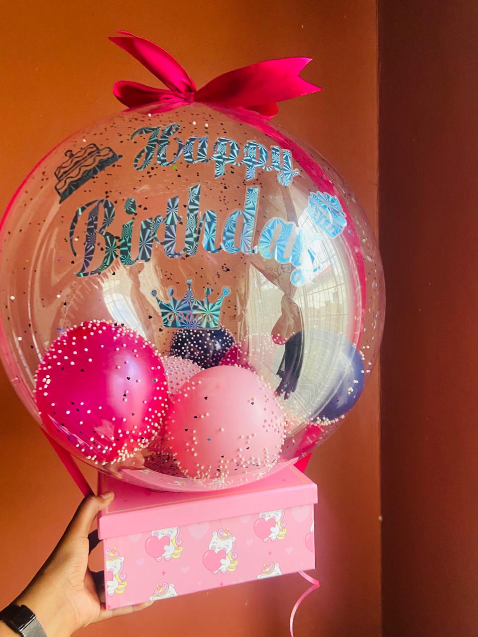 Birthday balloon arrangement above a pink gift box — presentation example