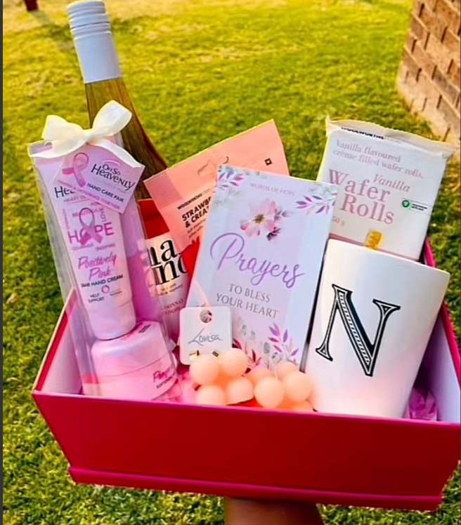 Pink gift box with an initial mug, candles and pamper treats — presentation example